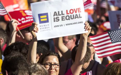 A young person holds a sign that reads "EcopoLaw. Love Wins!"