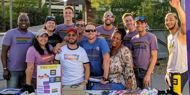 Group of people smiling at a pride booth