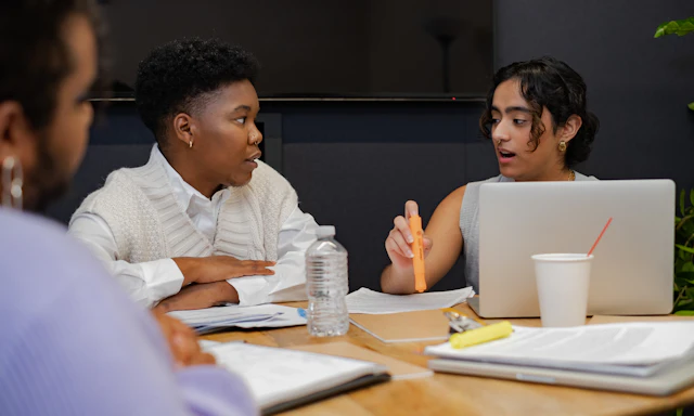 A trans person and a trans man discussing something in a meeting