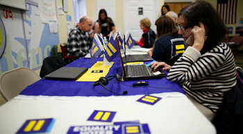 A woman makes calls at a table covered with HRC stickers.