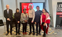 Diverse of six people standing in front of a presentation screen during a World AIDS Day conference.